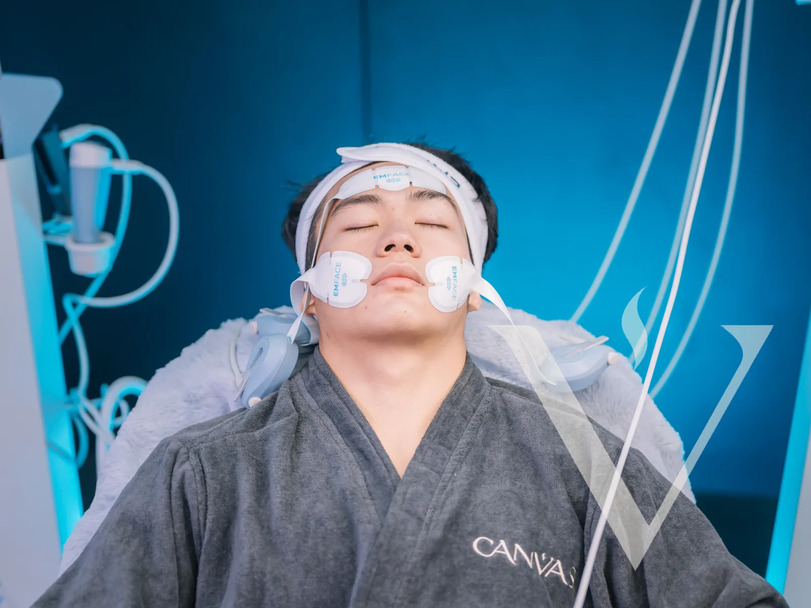 A client resting during an EMFACE session beside the treatment console at CANVAS Medical Clinic, Penang